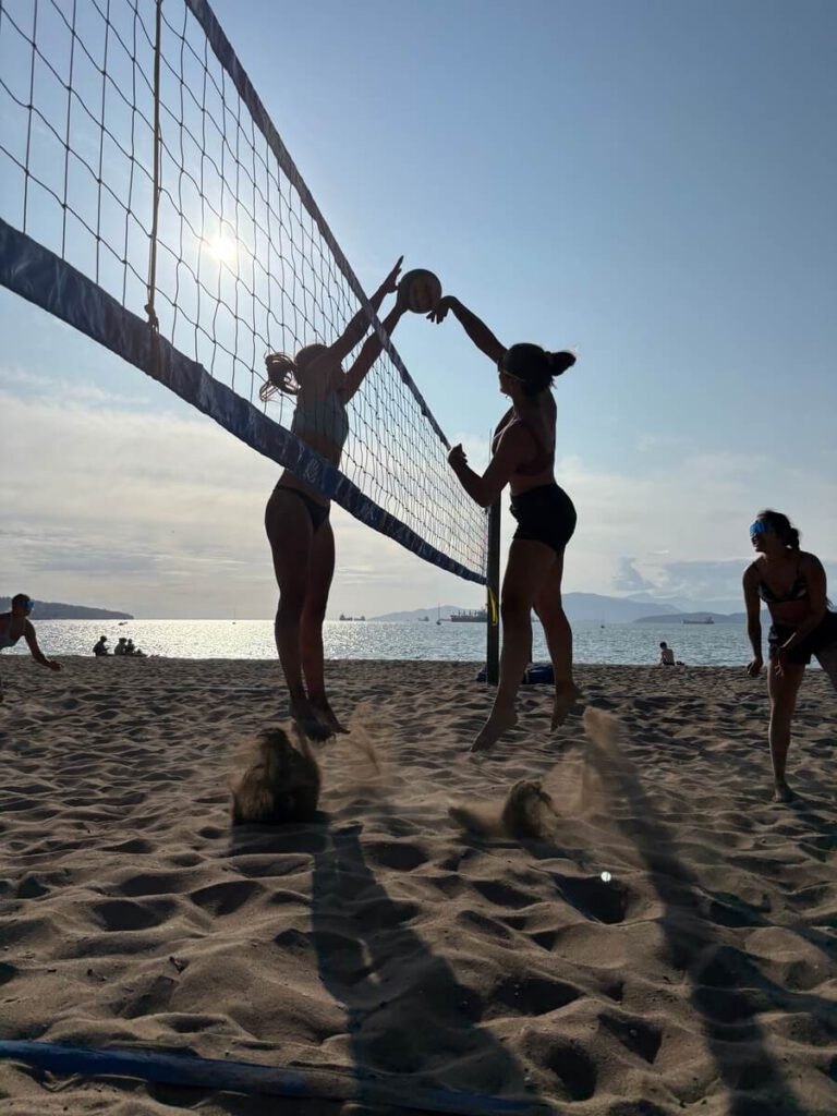 Two beach volleyball teams competing for a point at the net